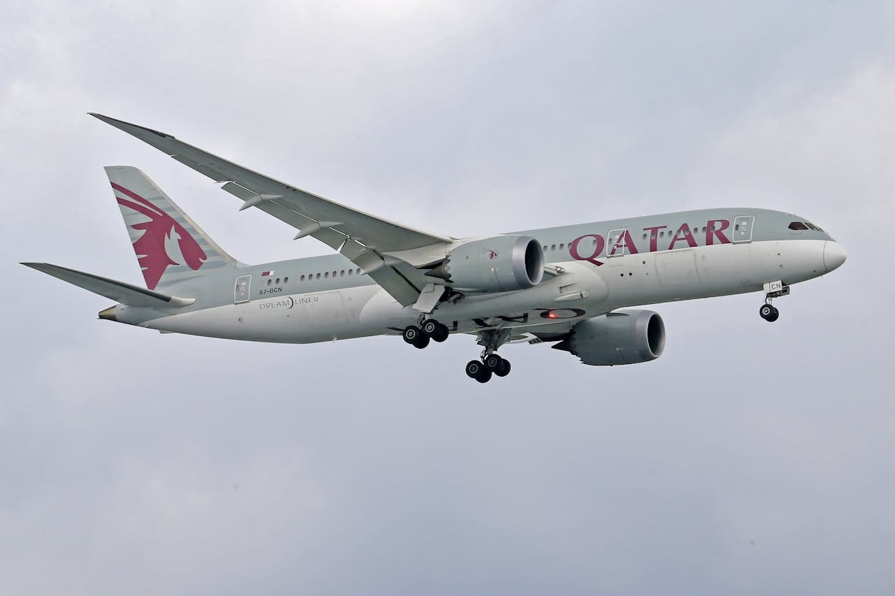 creative-03 Qatar Airways Boeing 787 Dreamliner soaring against a cloudy sky, showcasing aviation elegance.